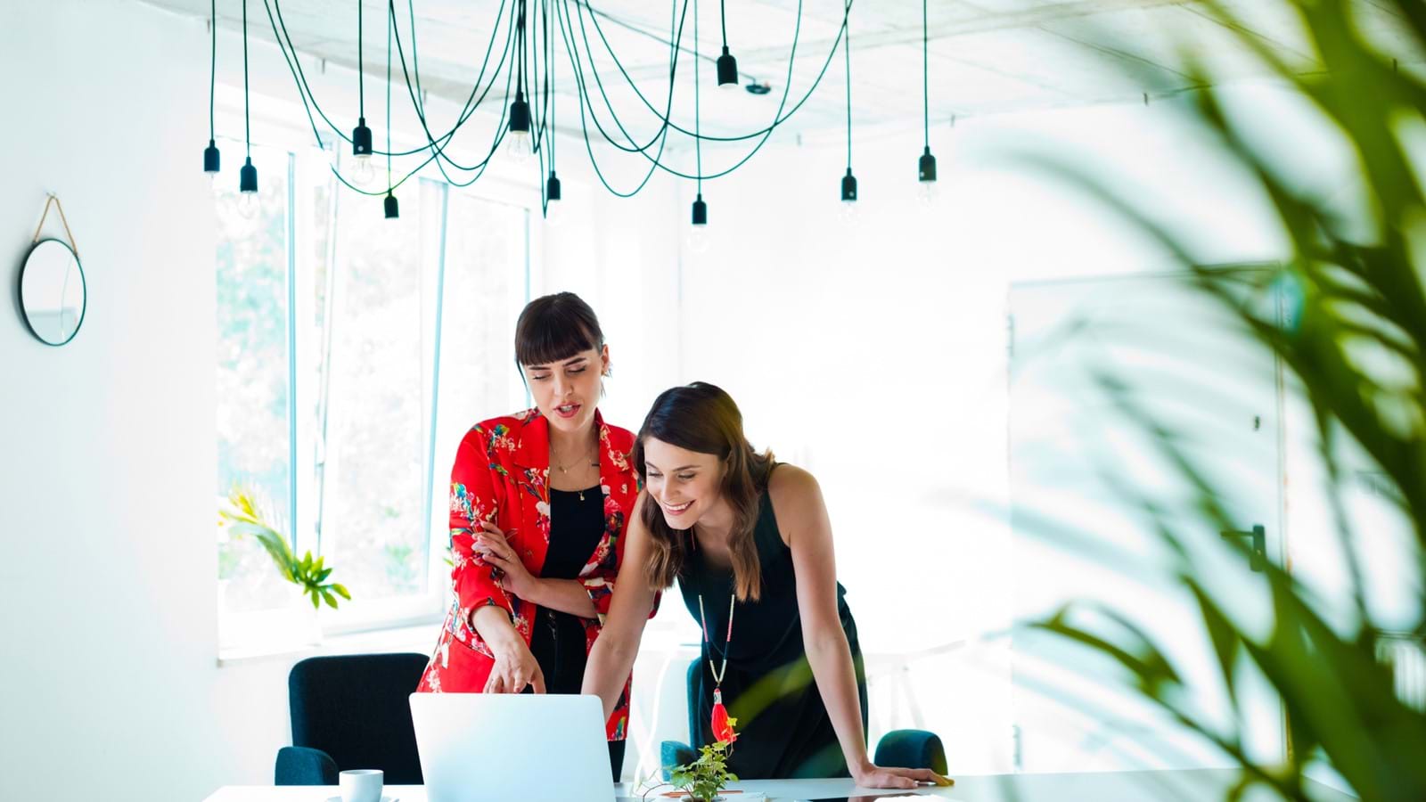 Two woman looking a laptop screen in a bright office space
