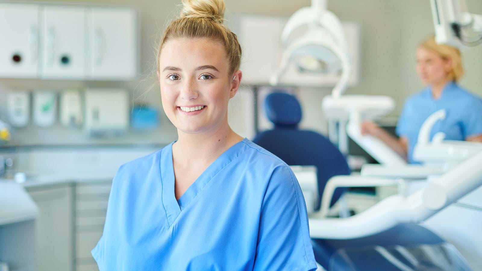 Female dentist smiling in front of dentist chair