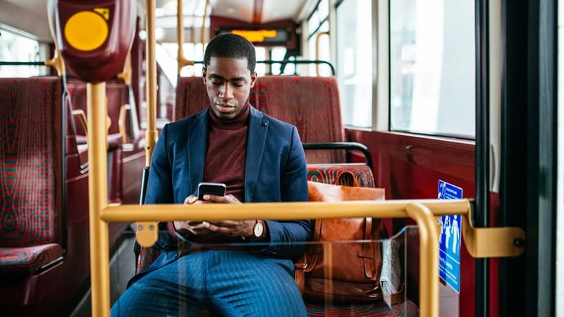 Ein Mitarbeiter kommuniziert mit seinen Kollegen im Bus über das mobile Intranet seines Unternehmens